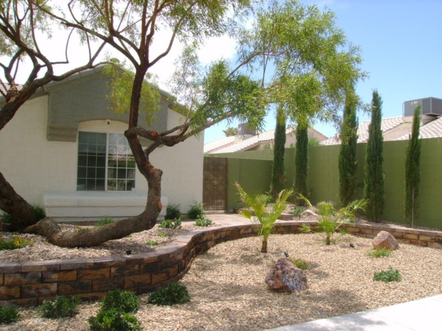 front yard with a large tree, rocks and tall plants
