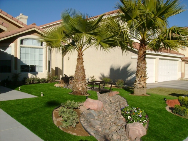 front yard with large trees, grass and small flowers