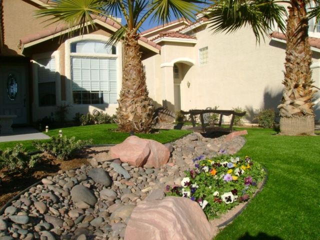 grassy yard with rocks, trees, and flowers
